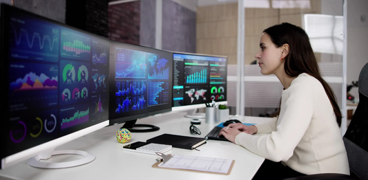 woman working on computer with 3 large monitors