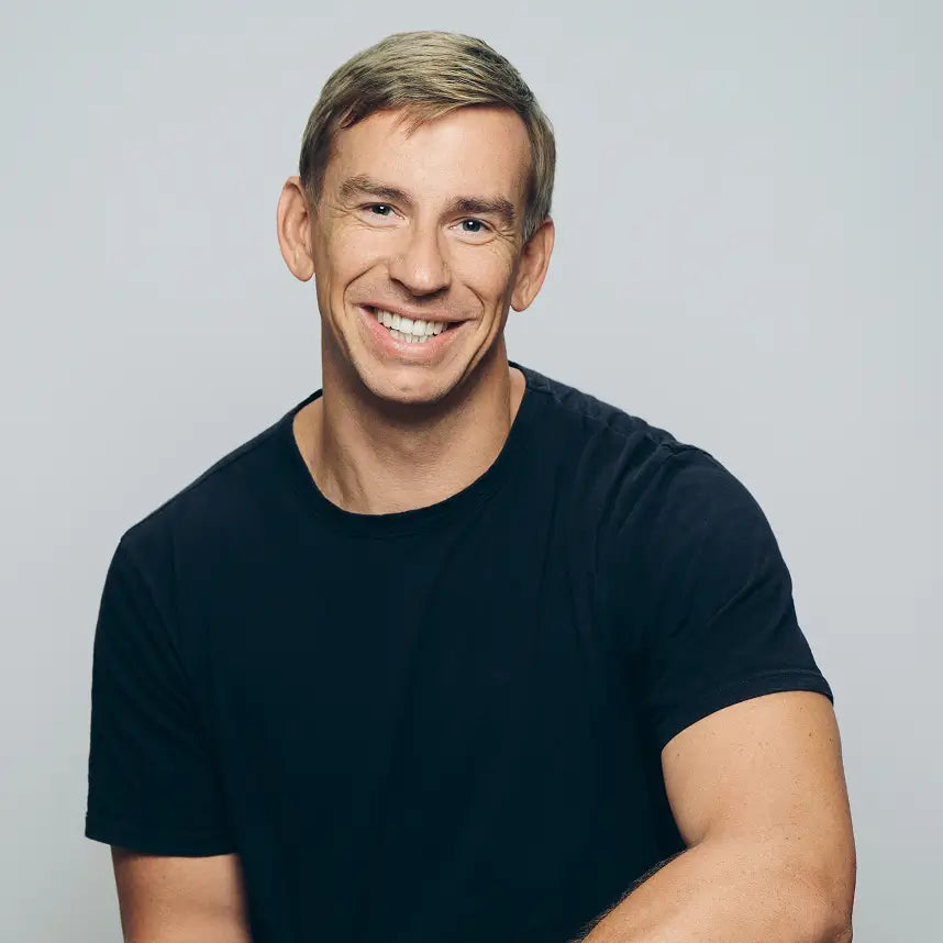 A Photo of Drew, a 40-ish white man with short blonde hair, he's wearing a navy crew neck tshirt and smiling directly  at the camera